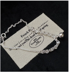 Détail d'un bracelet tressé argenté à plusieurs brins avec pendentif sphère et fermoir à ressort