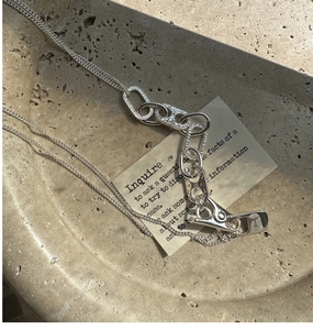 Dettaglio della chiusura a moschettone in argento S925 e targhetta incisa sulla collana