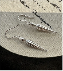 Macro detail of silver S925 teardrop earrings with vertical grooves on vintage linen