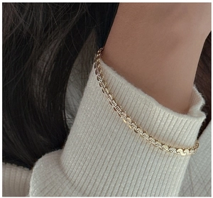 Detailed macro view of an S925 sterling silver gold gourd chain worn on a white knit cuff