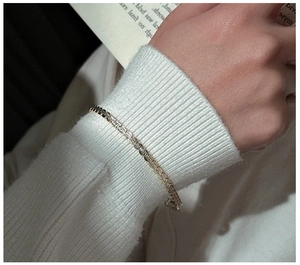 Close-up of a minimalist S925 sterling silver gourd chain bracelet on a white knit sweater