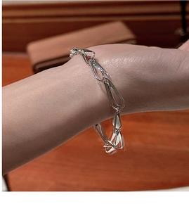 Detail view of a silver teardrop link chain bracelet worn on a female wrist in daily life