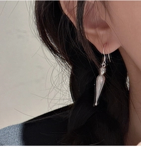 Detail of silver drop earrings with vertical ridges worn on ear for minimalist style
