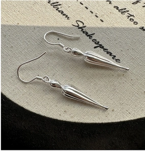 Detail of S925 sterling silver drop earrings with a polished mirror finish on a canvas backdrop