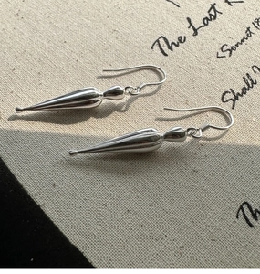 Macro shot of S925 sterling silver water drop earrings on vintage script linen background