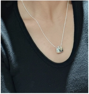 Macro shot of silver flask pendant necklace on neck showing mirror finish and chain