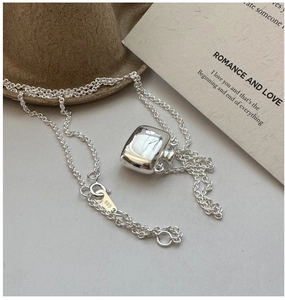 Macro detail of S925 sterling silver flask pendant with 925 hallmark on fine chain link
