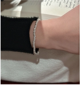 Detail of S925 sterling silver beaded bracelet worn over a black knitted sleeve