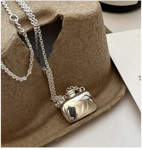 Macro detail of polished S925 silver flask pendant on a textured background