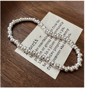 Macro detail of S925 sterling silver beaded bracelet with ribbed texture on wooden background