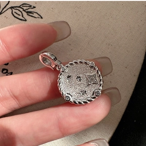 Macro detail of S925 silver coin pendant with textured surface and zircon star charms