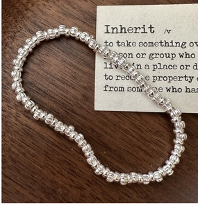 Detail view of S925 sterling silver textured beaded stretch bracelet on wooden surface