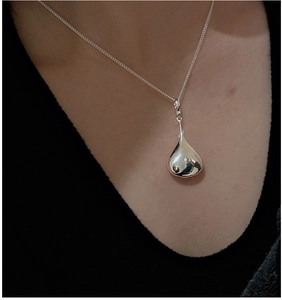 Close-up of a minimalist S925 silver hollow teardrop pendant on a fine necklace chain