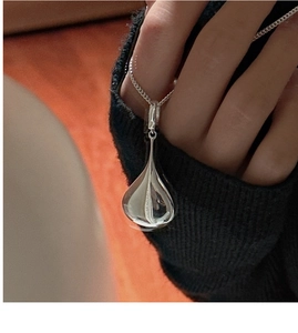 Close-up of a hollow 3D teardrop pendant in polished S925 silver on a delicate chain