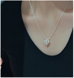 Macro detail of a ribbed teardrop pendant on a silver snake chain around a model's neck