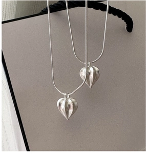 Close-up of S925 sterling silver fruit pendant on thin snake chain over grey packaging