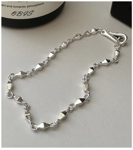 Gros plan sur un bracelet en argent sterling S925 avec perles losanges et fermoir en S minimal