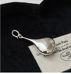 Macro shot of 3D hollow teardrop silver pendant on textured black fabric background