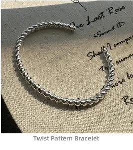Detail des gedrehten Kabeldesigns an einem silbernen minimalistischen offenen Armreif im Licht