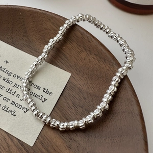 Minimalist S925 sterling silver beaded bracelet with textured drum beads on wooden tray