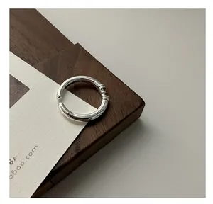 Detail of S925 sterling silver adjustable ring with threaded accents on a wooden block