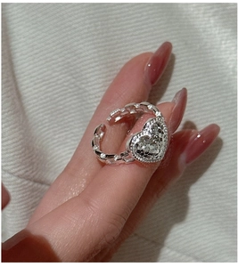 Macro detail of silver heart ring featuring textured surface and chain-link adjustable band