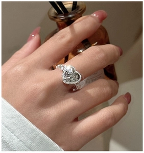 Detail of S925 silver heart ring with pavé crystals and twisted rope band on finger