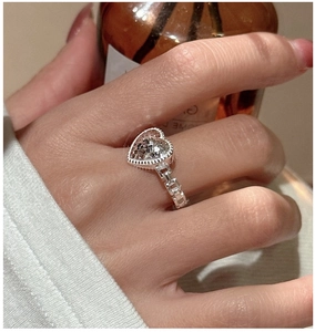 Macro detail of silver heart ring featuring a unique chain style band and sparkling inlay