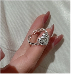 Detail of silver heart ring with crushed ice texture and chain-link band on finger