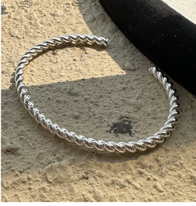 Detailansicht des gedrehten Manschettenarmbands aus 925er Sterlingsilber auf Stein