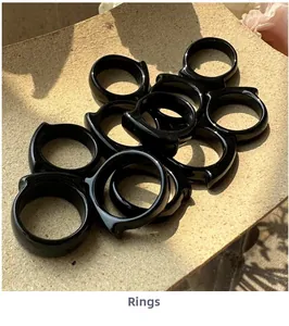 Macro shot of black agate resin rings stacked on beige paper under natural leaf shadows