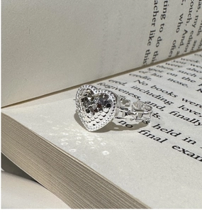 Close-up of S925 sterling silver heart ring with textured surface on vintage book