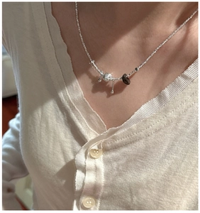 Detail of S925 silver necklace with textured bead, dark stone and metal drop pendants