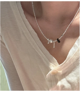 Detail of S925 silver necklace with crushed stone pendant on ribbed knit top