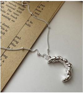 Détail macro du collier lune en argent S925 avec texture lave sur papier vintage