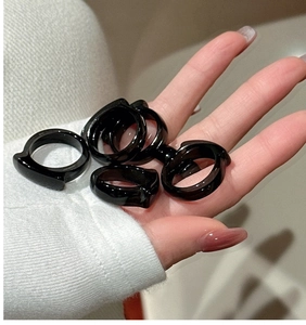 Close-up of minimalist black geometric rings with a glossy finish on a hand