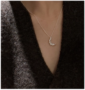 Gros plan d'un collier lune en argent S925 avec texture lave vintage et chaîne à perles