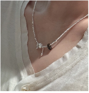 Close-up of S925 silver beaded necklace with shell pendant and brown gemstone on a model