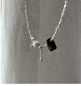 Detail of S925 silver necklace with textured sphere, wood block and teardrop charm