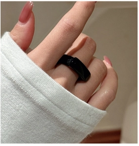Close-up of minimalist black resin ring with a polished square flat top on a finger