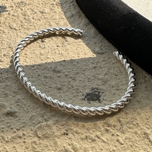 Polierter 925 Sterling Silber gedrehter Seil-Armreif auf einer Steinoberfläche