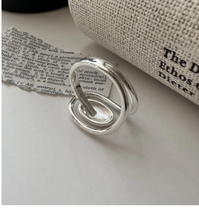 Macro detail of silver S925 oval ring with intertwined bands on vintage paper background