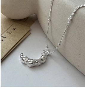 Détail du collier croissant de lune argenté avec texture rétro sur socle céramique