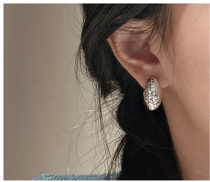 Close-up of diamond-cut S925 sterling silver hoop earrings worn on ear for women