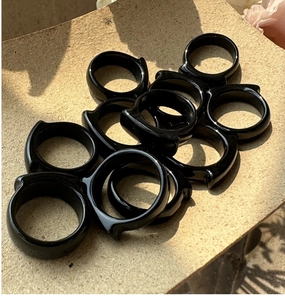 Close-up of black resin rings with cat ear design on a textured beige surface