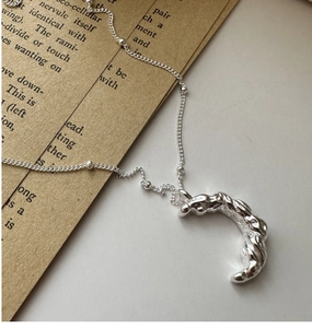 Gros plan d'un pendentif lune en argent avec texture martelée et détails de chaîne à billes