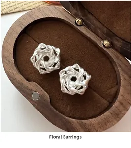 Detailed macro view of S925 sterling silver matte rose earrings in a wooden jewelry box