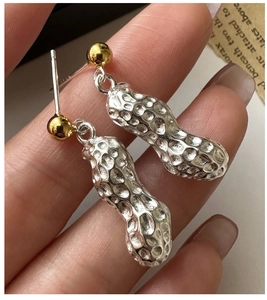 Détail macro de boucles d'oreilles cacahuète en argent S925 avec clou doré et texture