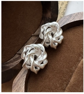 Macro shot of matte silver rose earrings featuring a unique twisted floral texture