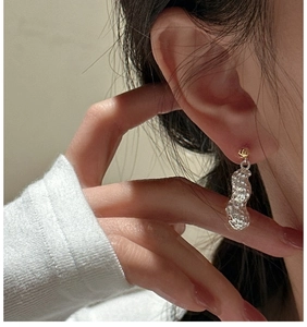 Détail de boucles d'oreilles créatives en forme de cacahuète avec texture martelée